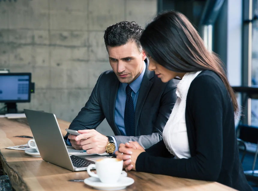 Handsome-businessman-and-beautiful-businesswoman-using-laptop-together-in-cafe